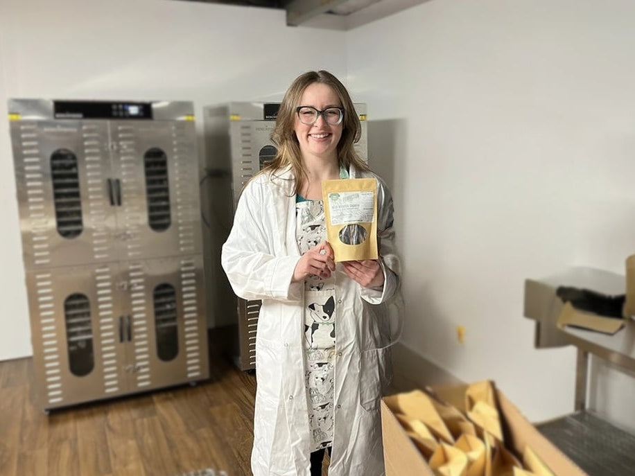 Pawfection founder in a lab coat holding their product package at Pawfection HQ. 